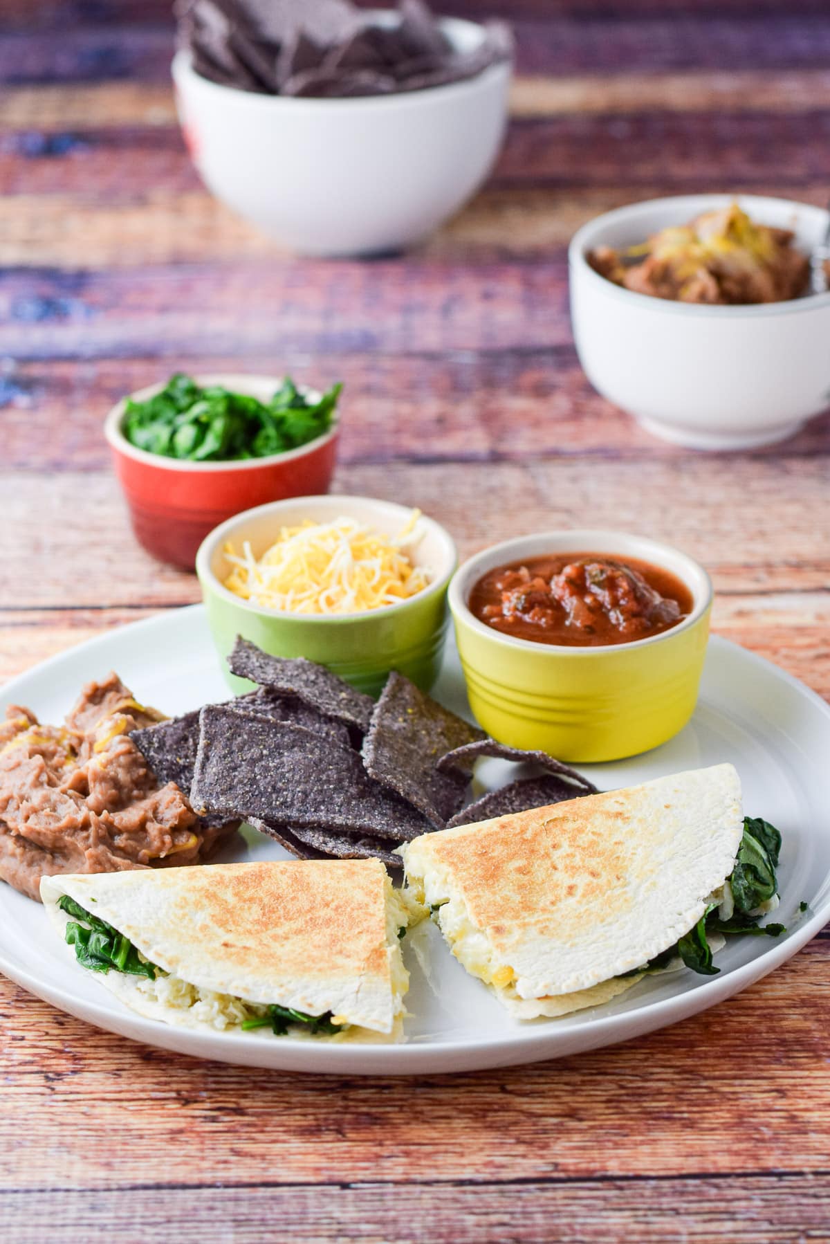 Chips, beans, cheese, and salsa on the plate with the quesadillas