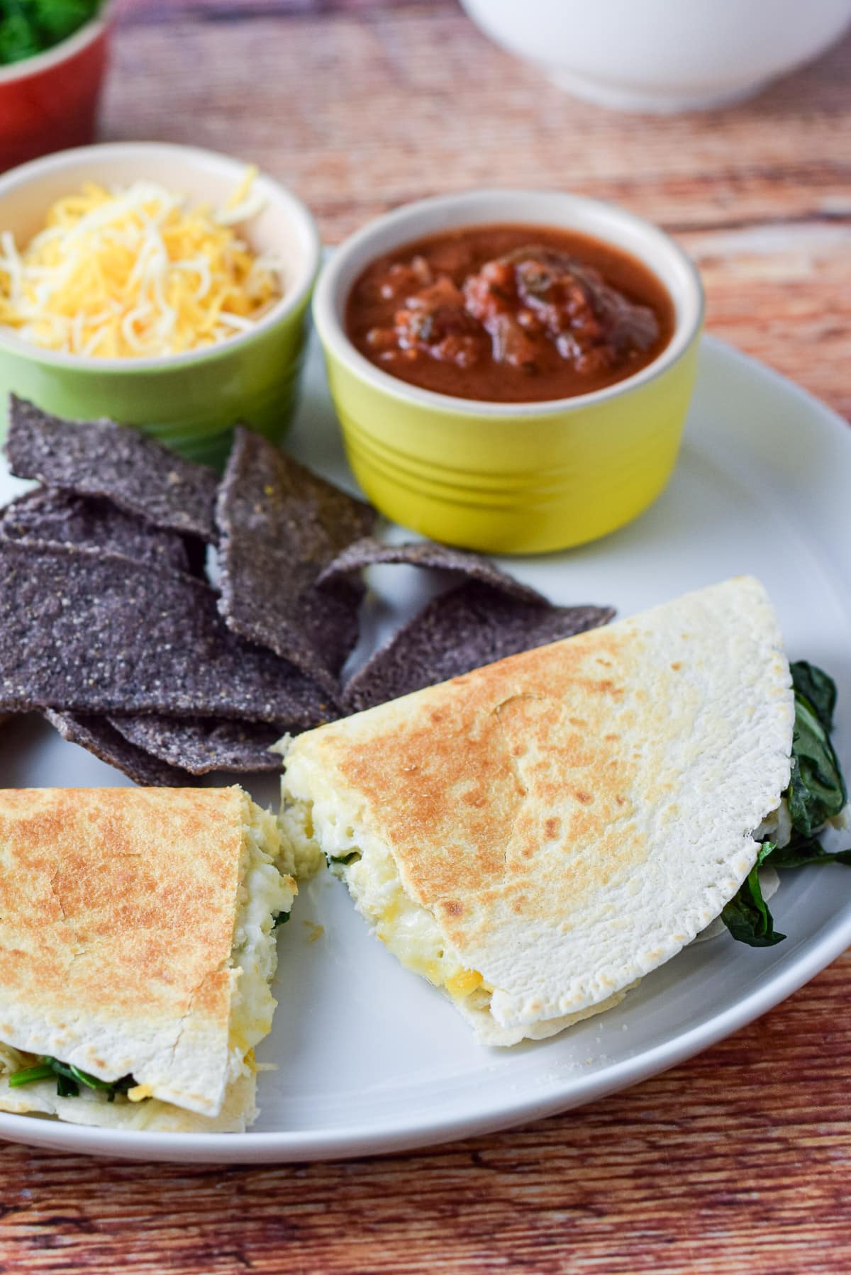 Close view of the quesadilla with chips, salsa and cheese on the plate