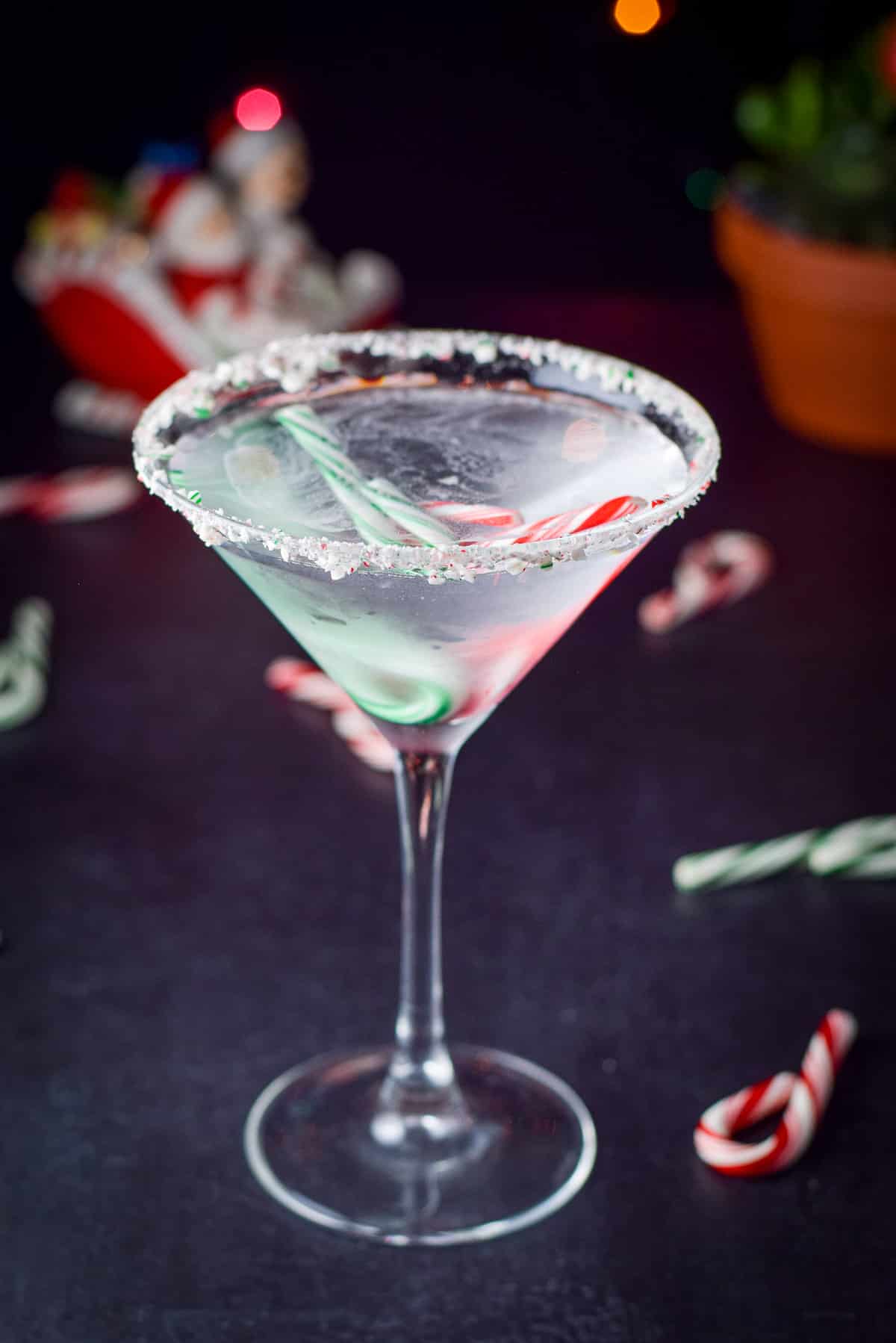 closer view of the clear cocktail in a martini glass with candy canes in it and on the rim