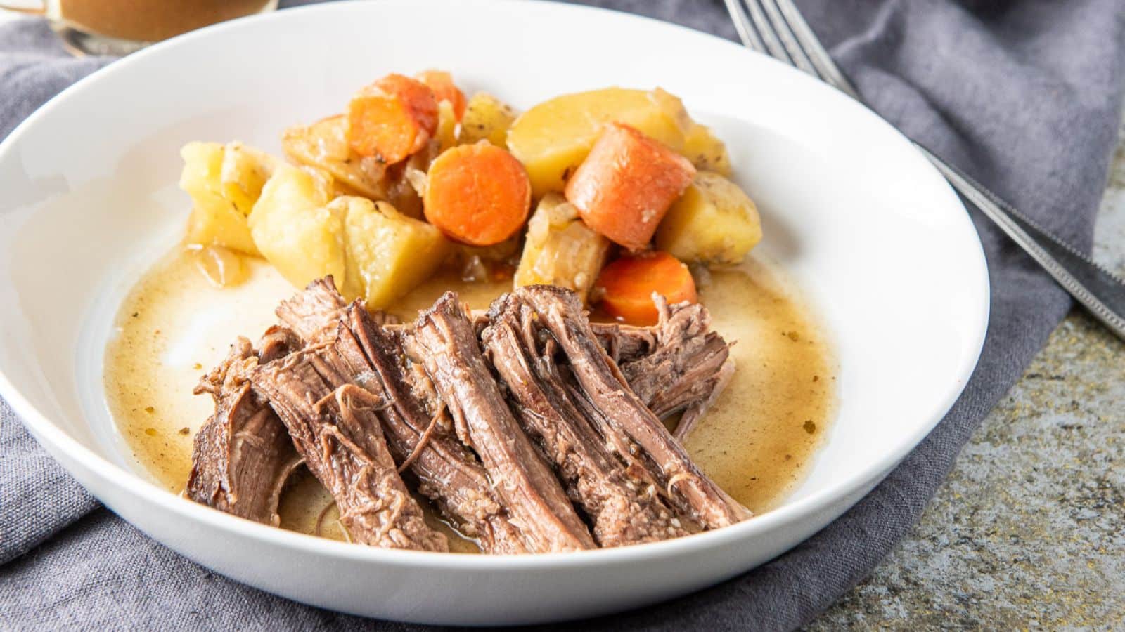 A white deep bowl with shredded beef, potatoes, and carrots
