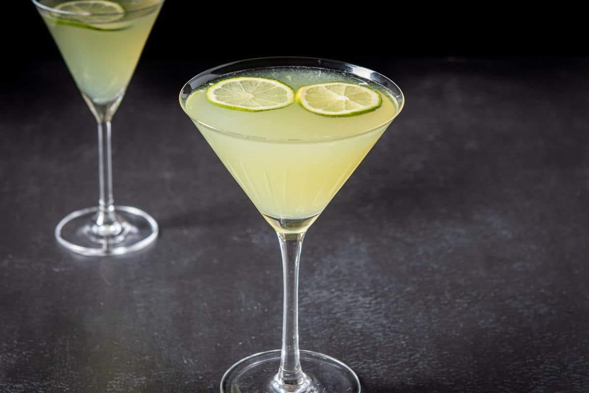Two cocktail glasses filled with the lime cocktail with two limes floating as garnish