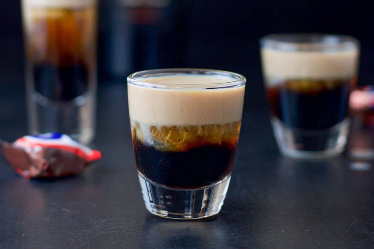 three shot glasses filled with a layered shot