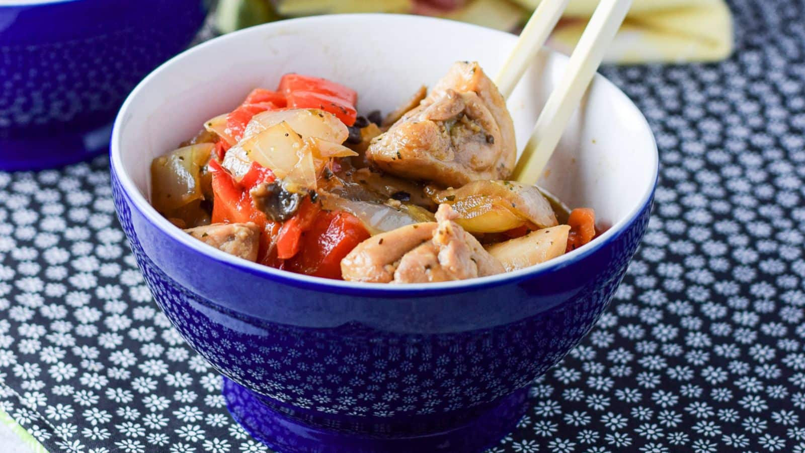 two blue bowls filled with stir fry on a blue placemat