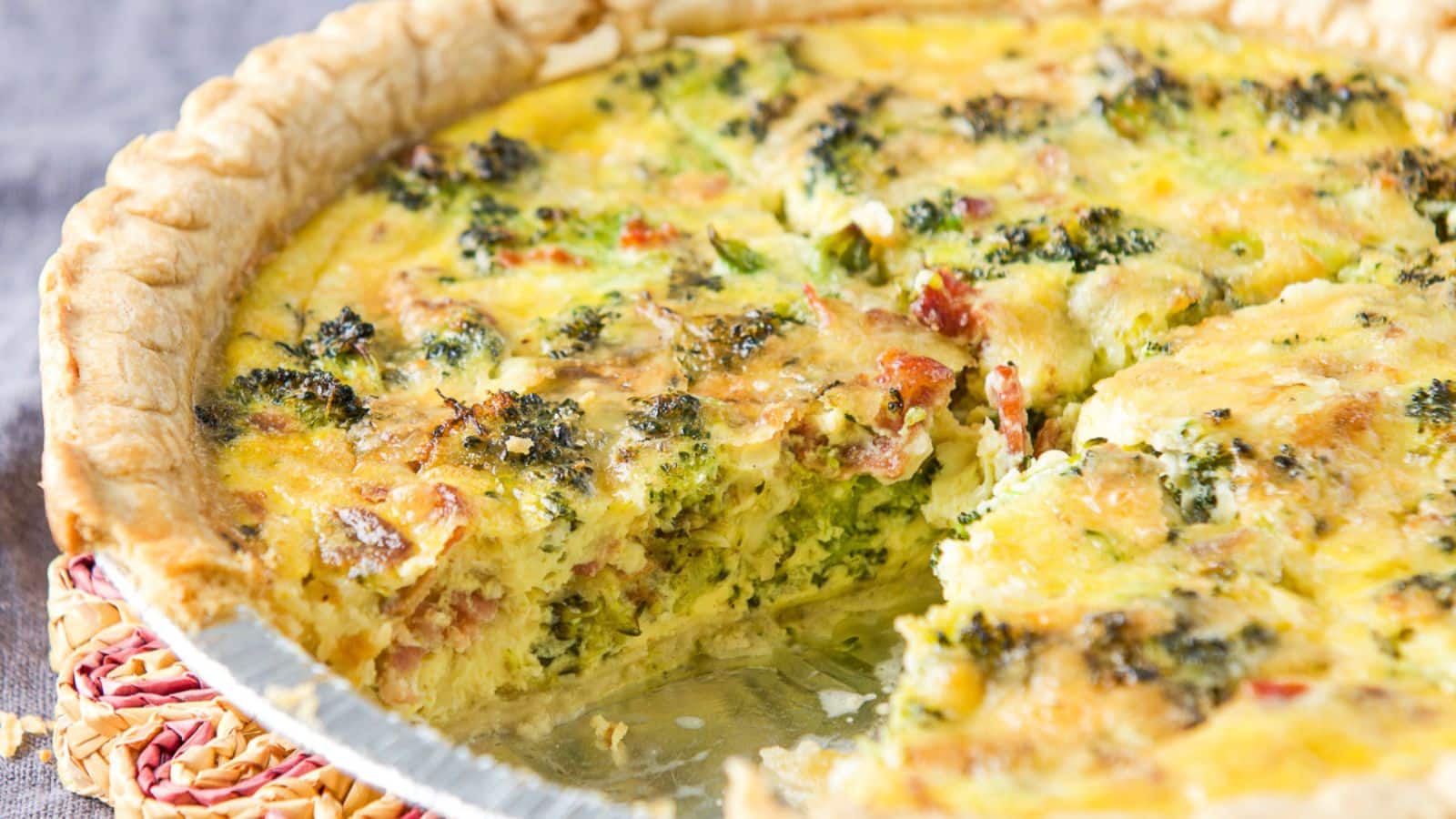 a pie plate with quiche in it with a piece cut out