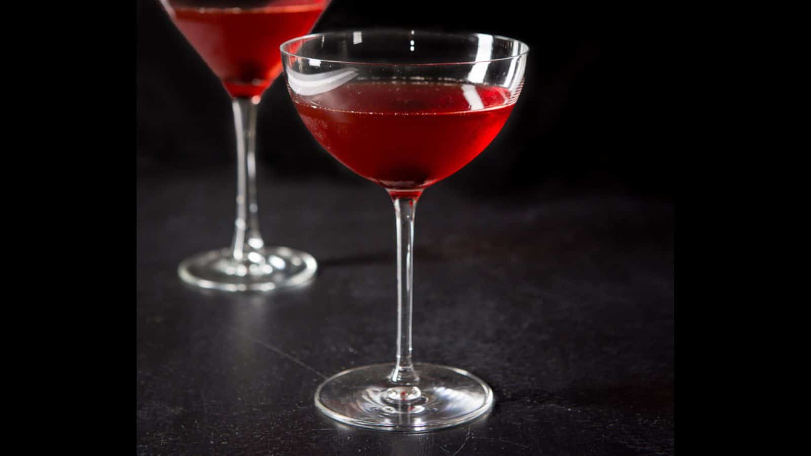 Two martini glasses filled with the Manhattan with a cherry in the glass