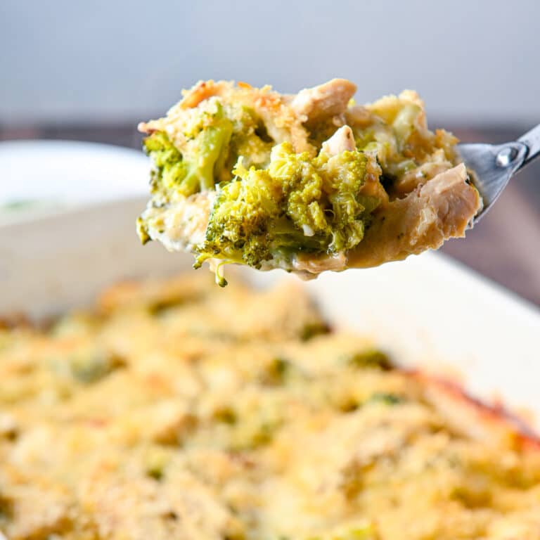 A big spoon with a scoop of chicken, broccoli, cheese, and sauce on it held over the pan - square
