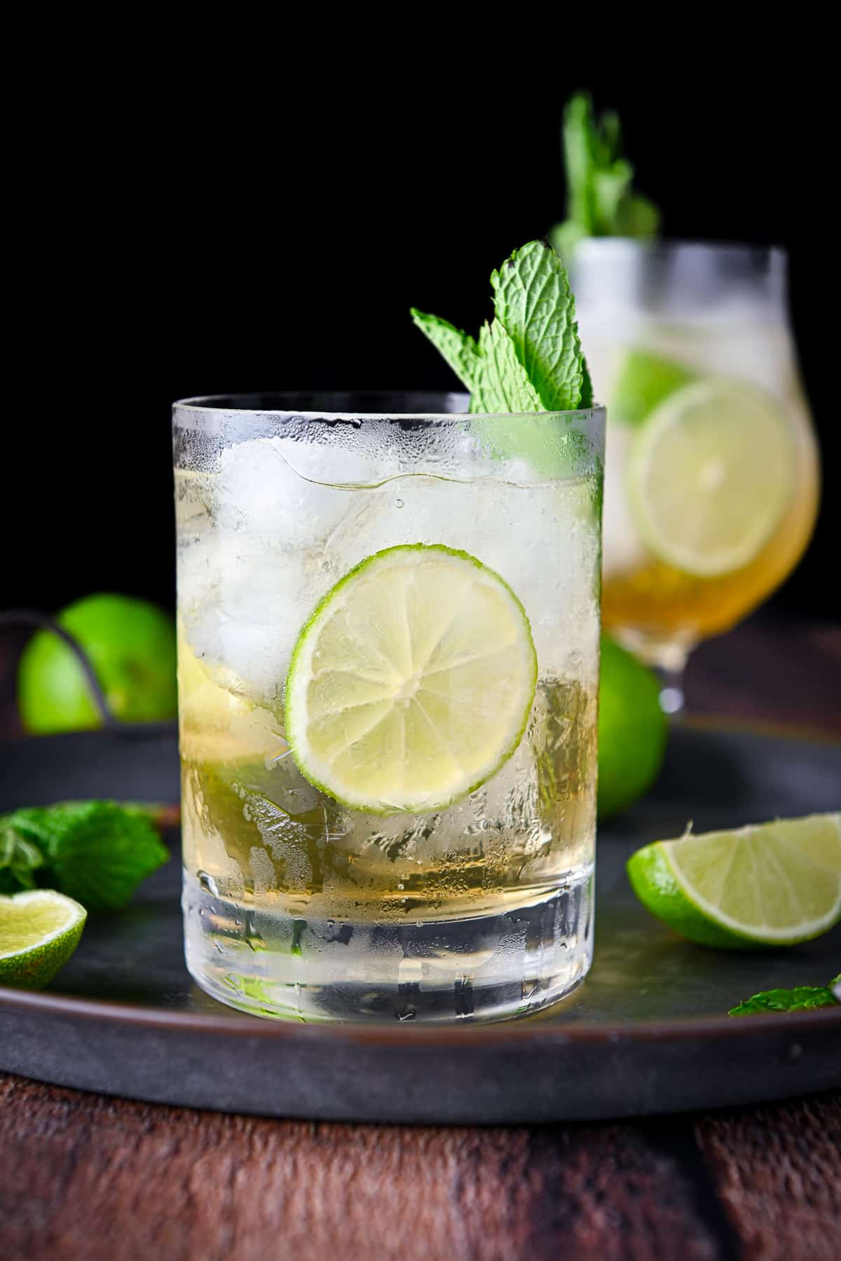 Vertical view of the prosecco cocktail with lime and mint in as garnish and on the tray as well