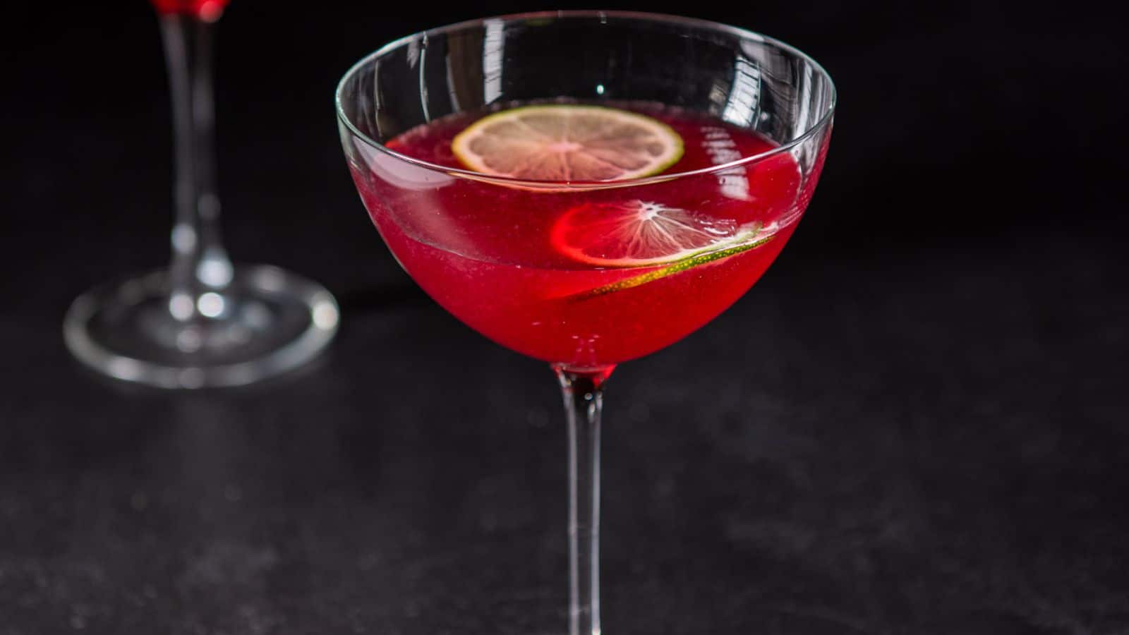 A bowl glass filled with the red drink with lime wheels floating on top