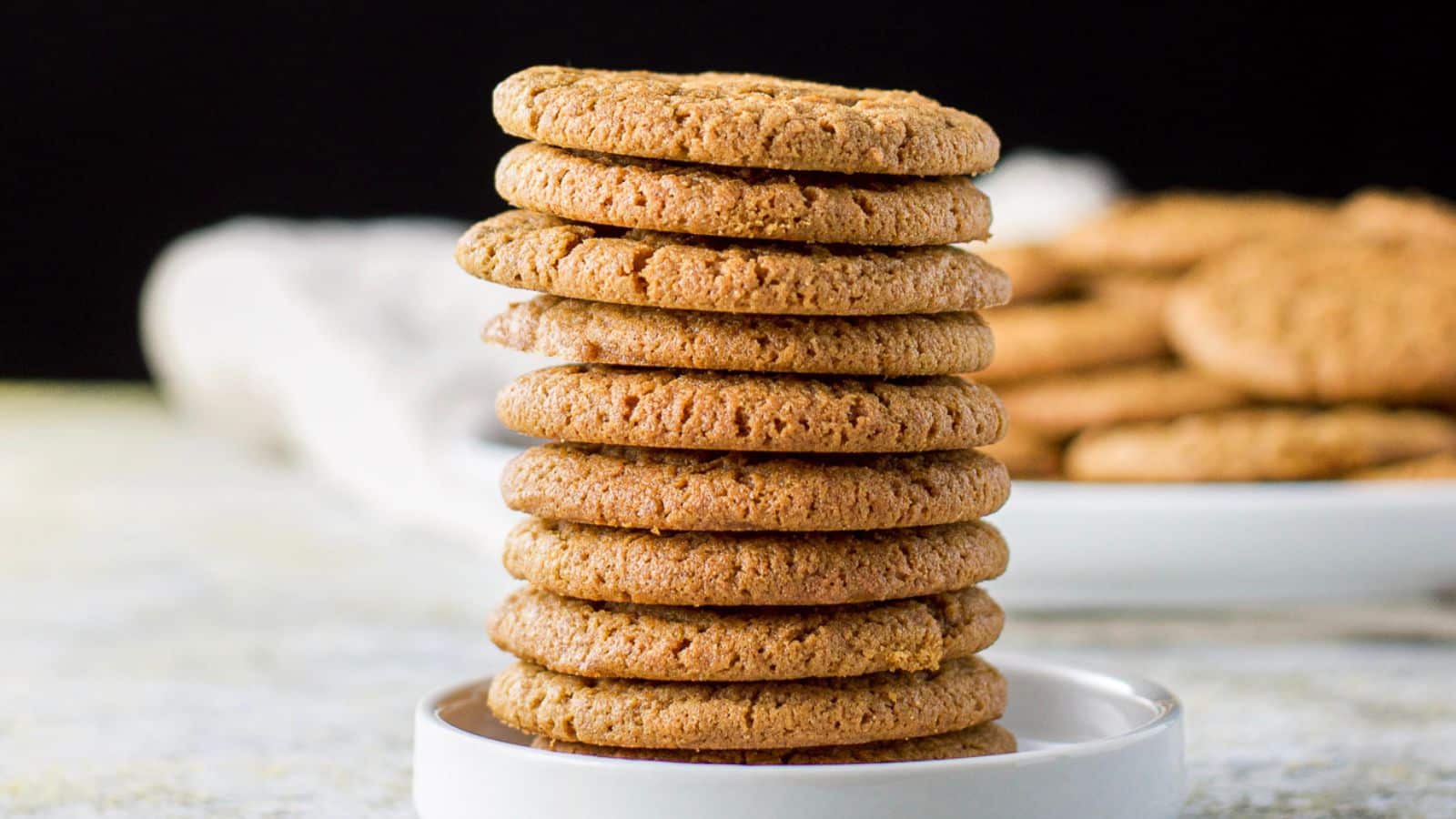 a small plate with a bunch of cookies in a stack with more in the background