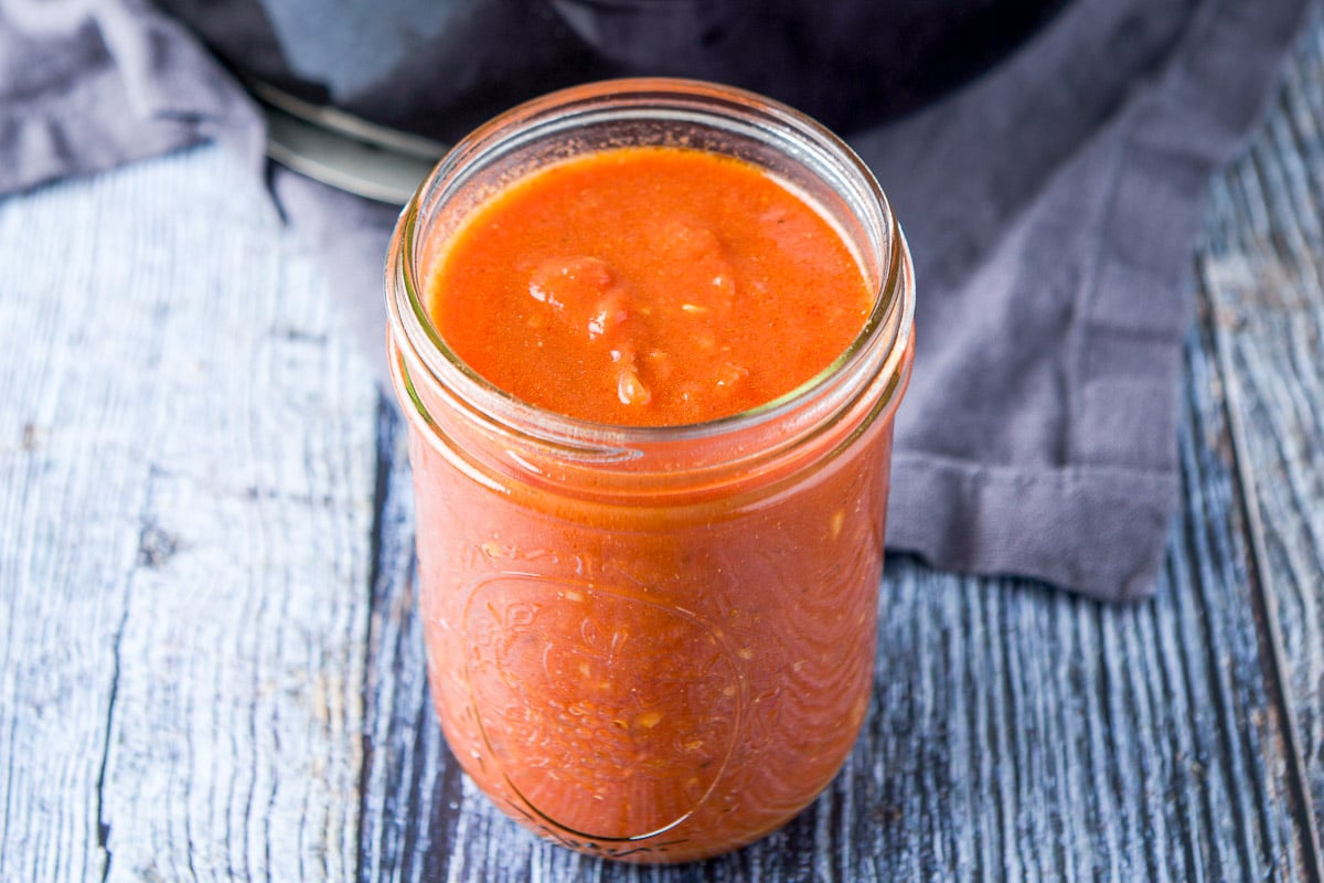 a jar filled with red pasta sauce on a table