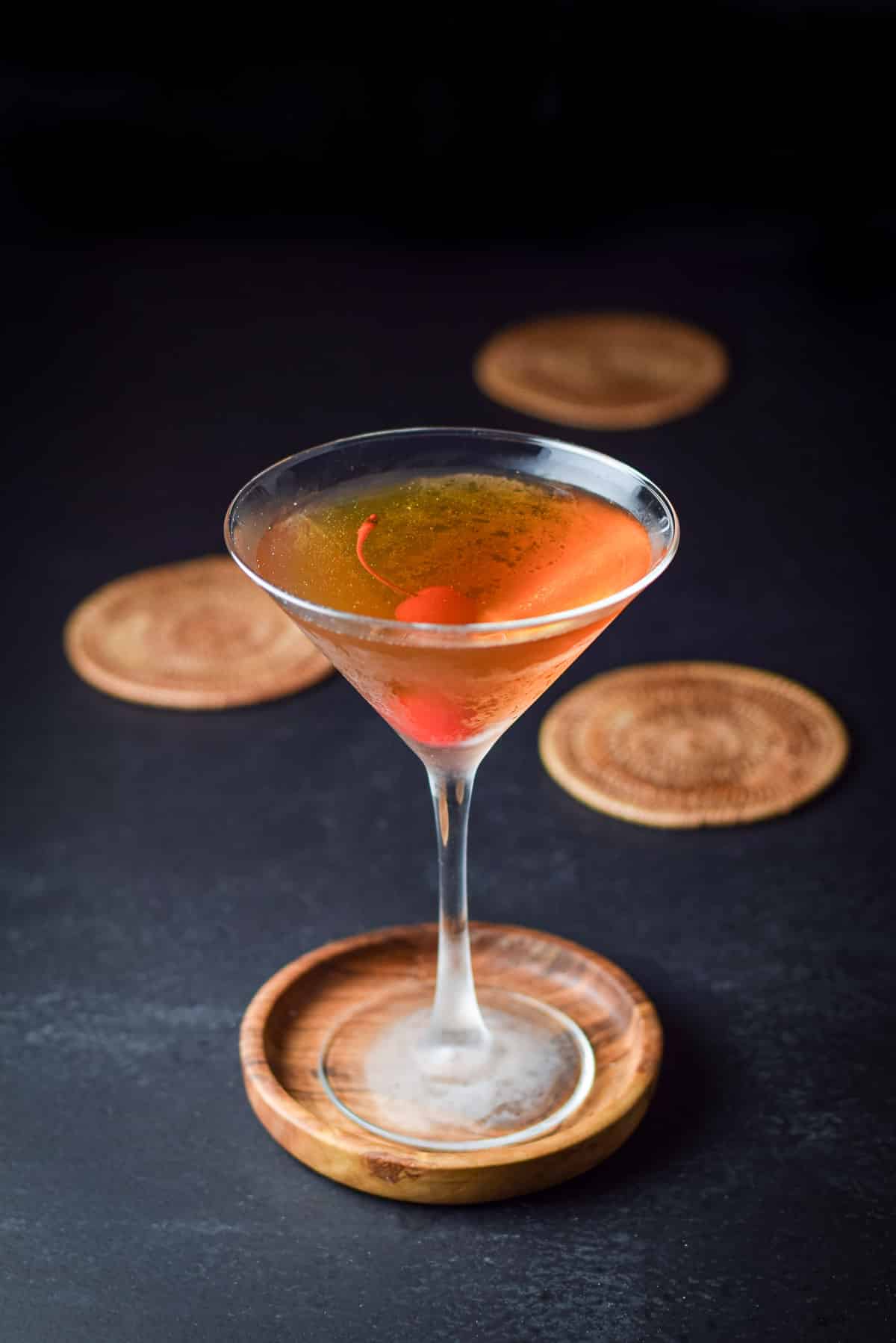 A frosty martini glass with the cocktail in it along with a cherry