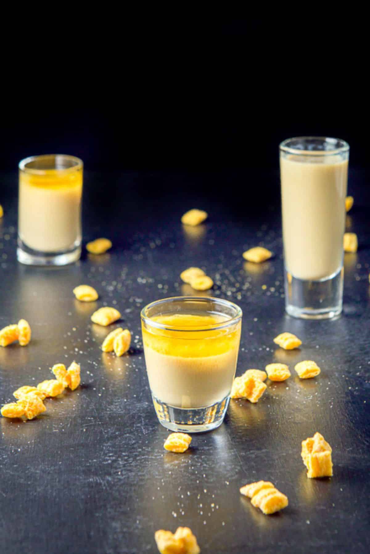Short glass in front filled with the layered shot with cereal and the tow other shots in the background