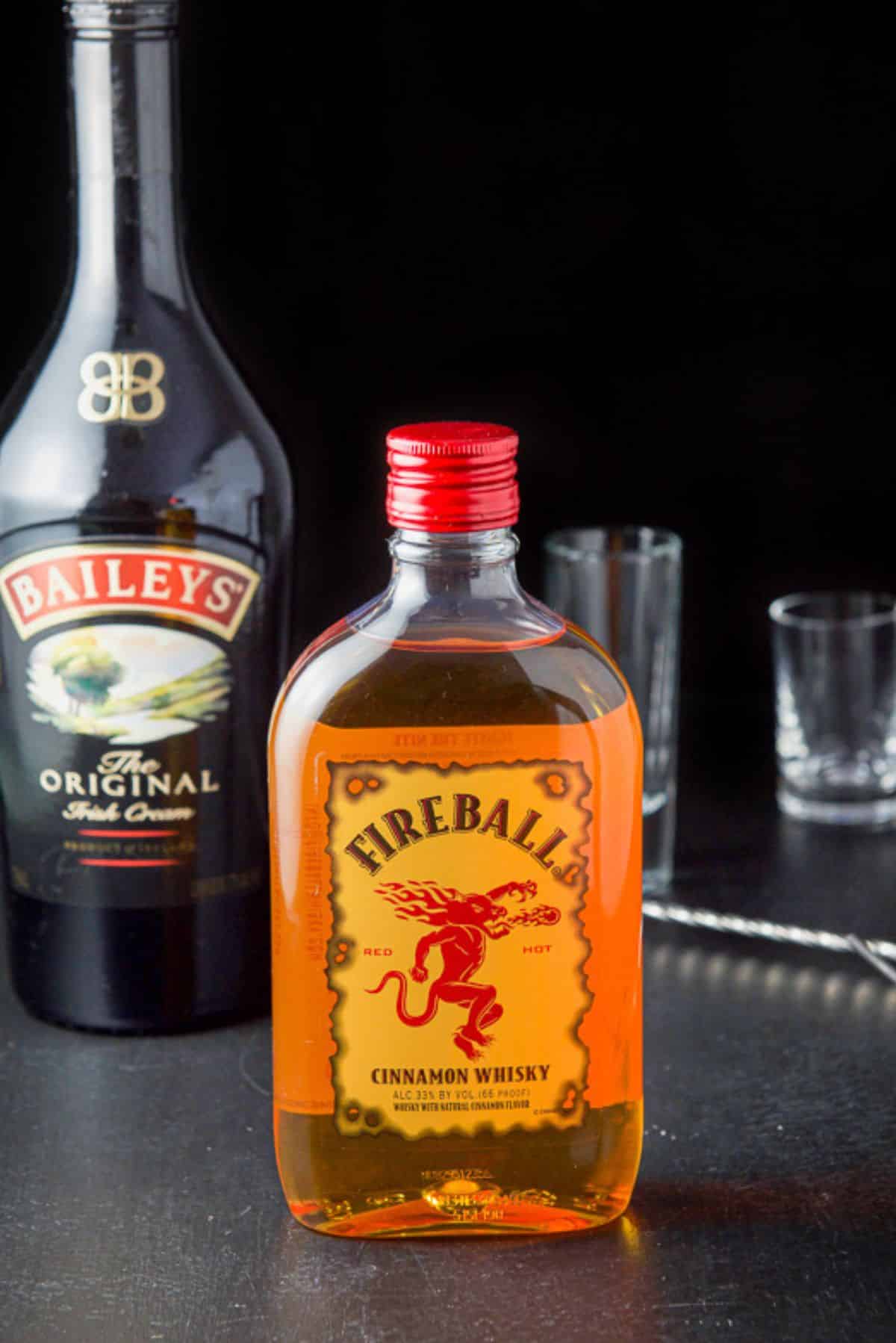 Fireball whiskey and Baileys Irish cream along with a pourer, spoon and glassware on the table