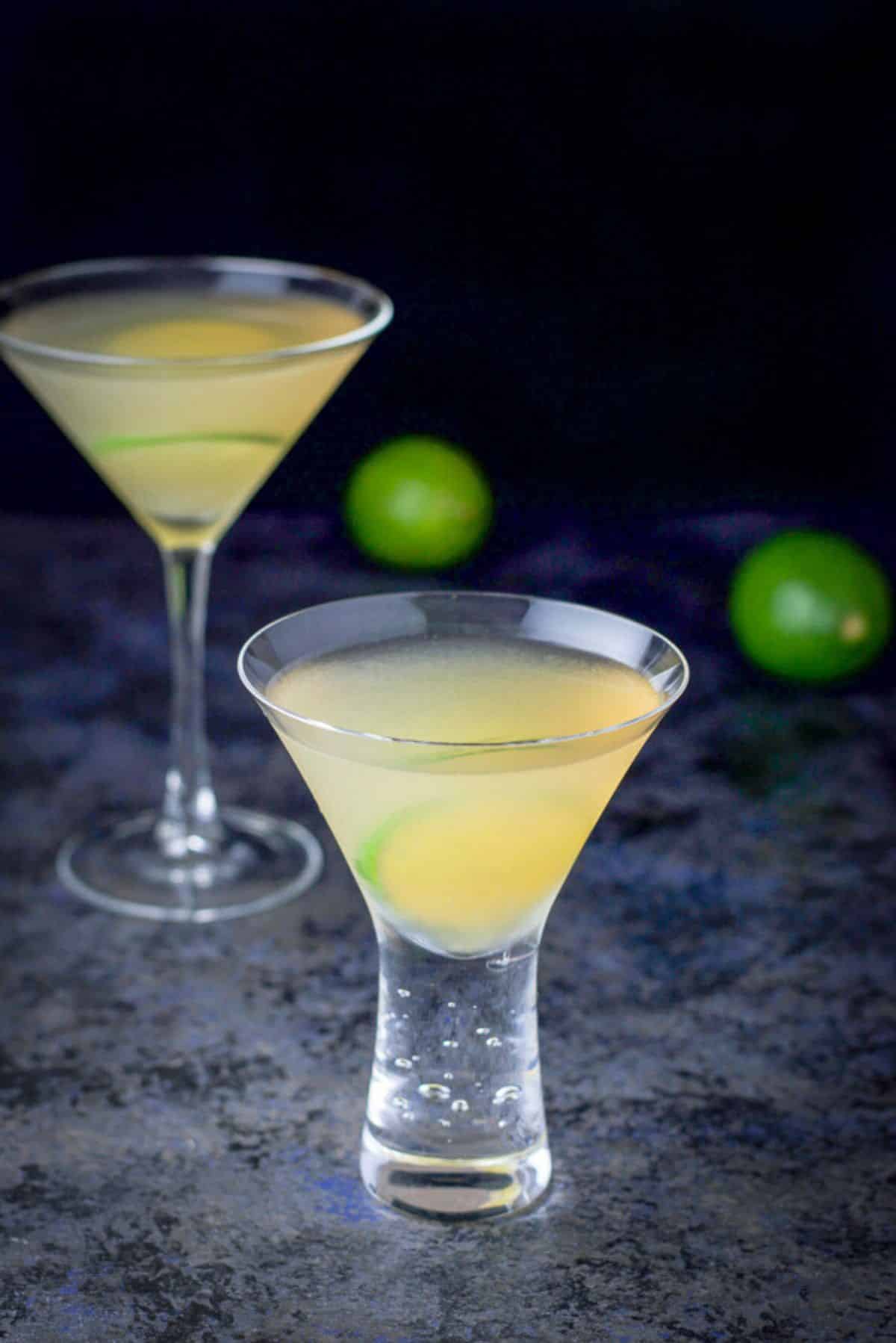 shorter bubble martini glass of the cocktail in front and the taller one behind