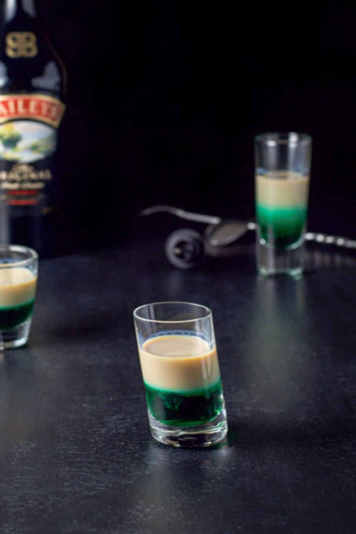 Baileys Irish cream layered into the three glasses with the spoon and bottle in the background
