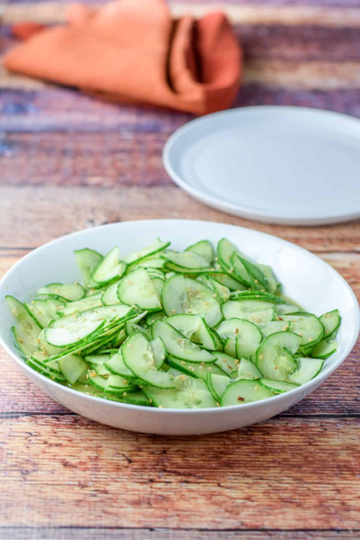 Dressing on the cucumber salad in a shallow bowl on the table