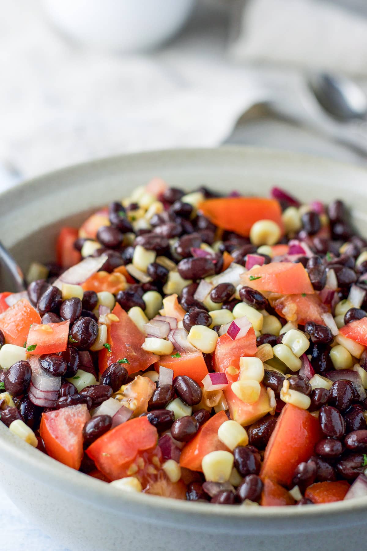 Close up of the big beige serving bowl of black beans, corn, tomatoes and onion