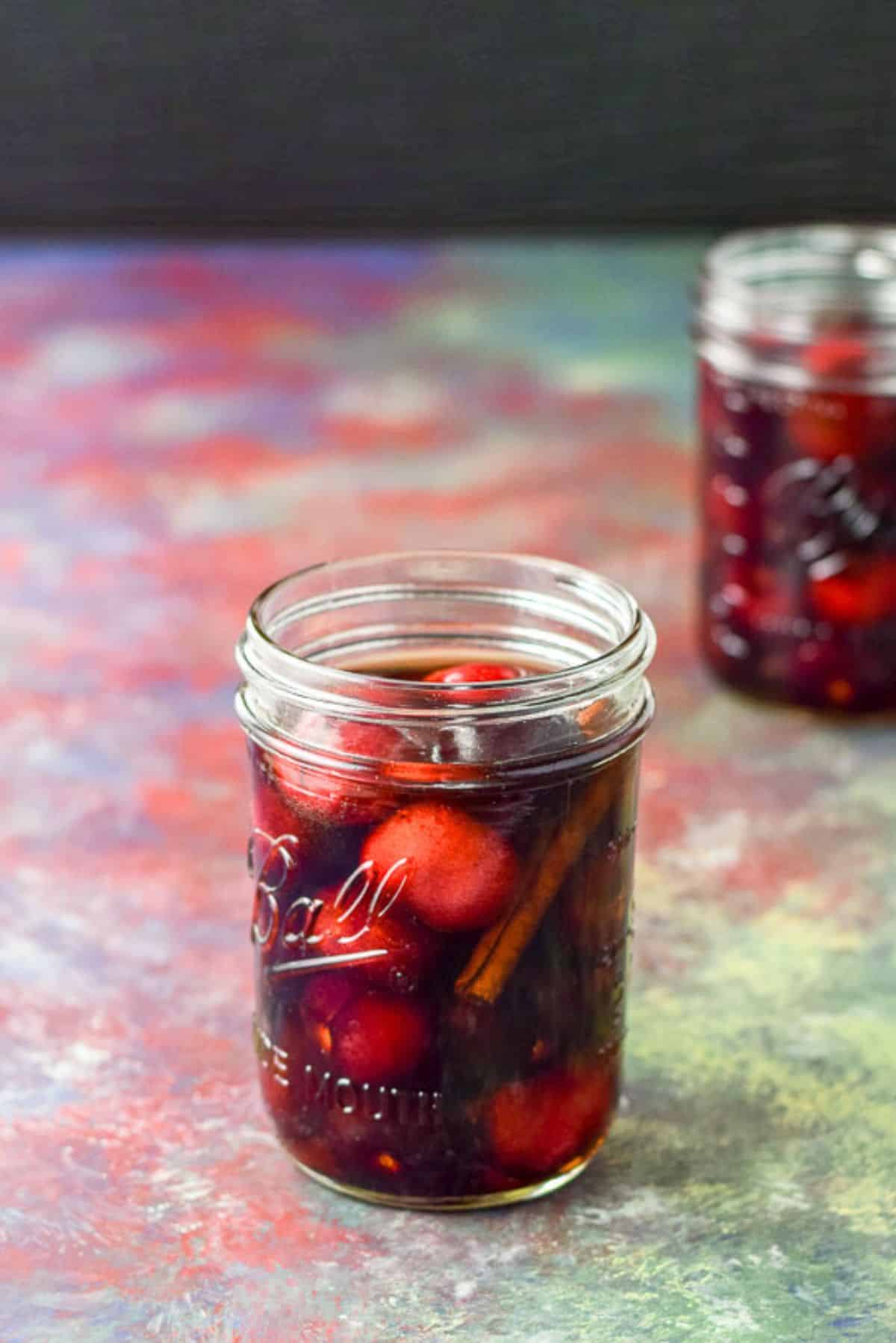 Two jars of Bourbon soaked cherries Cherries and cinnamon in bourbon in two jars on a table