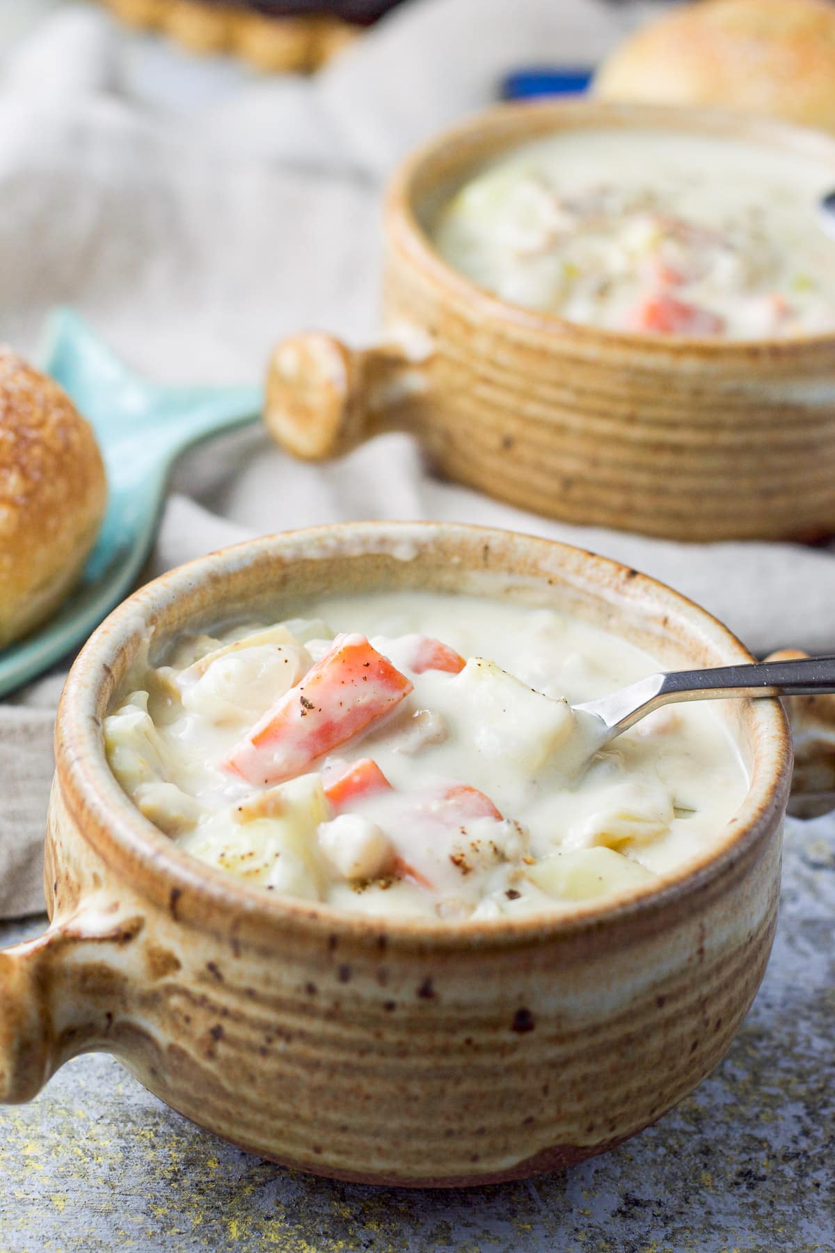 Spoon is in the crock of chowder with another crock in the background