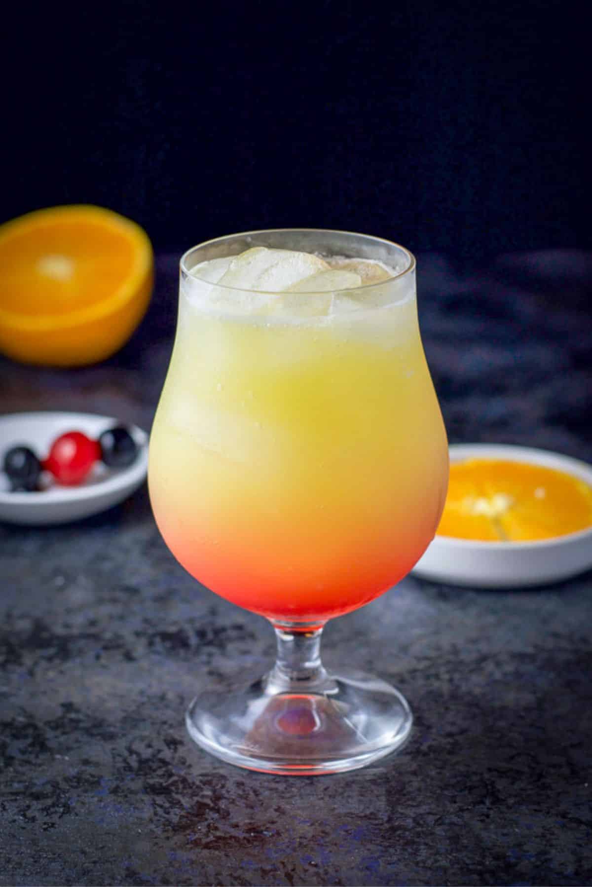 Grenadine poured into the glass of the tequila sunrise cocktail ready to be garnished
