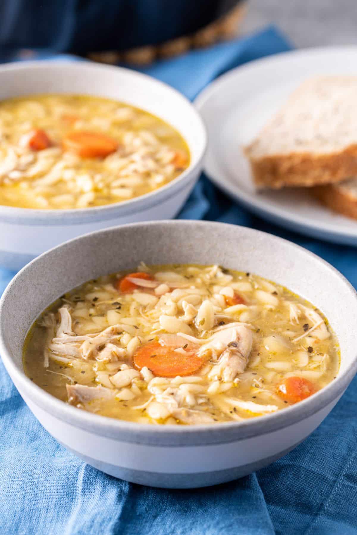 Closer view of the chicken soup in two bowls with bread in the background