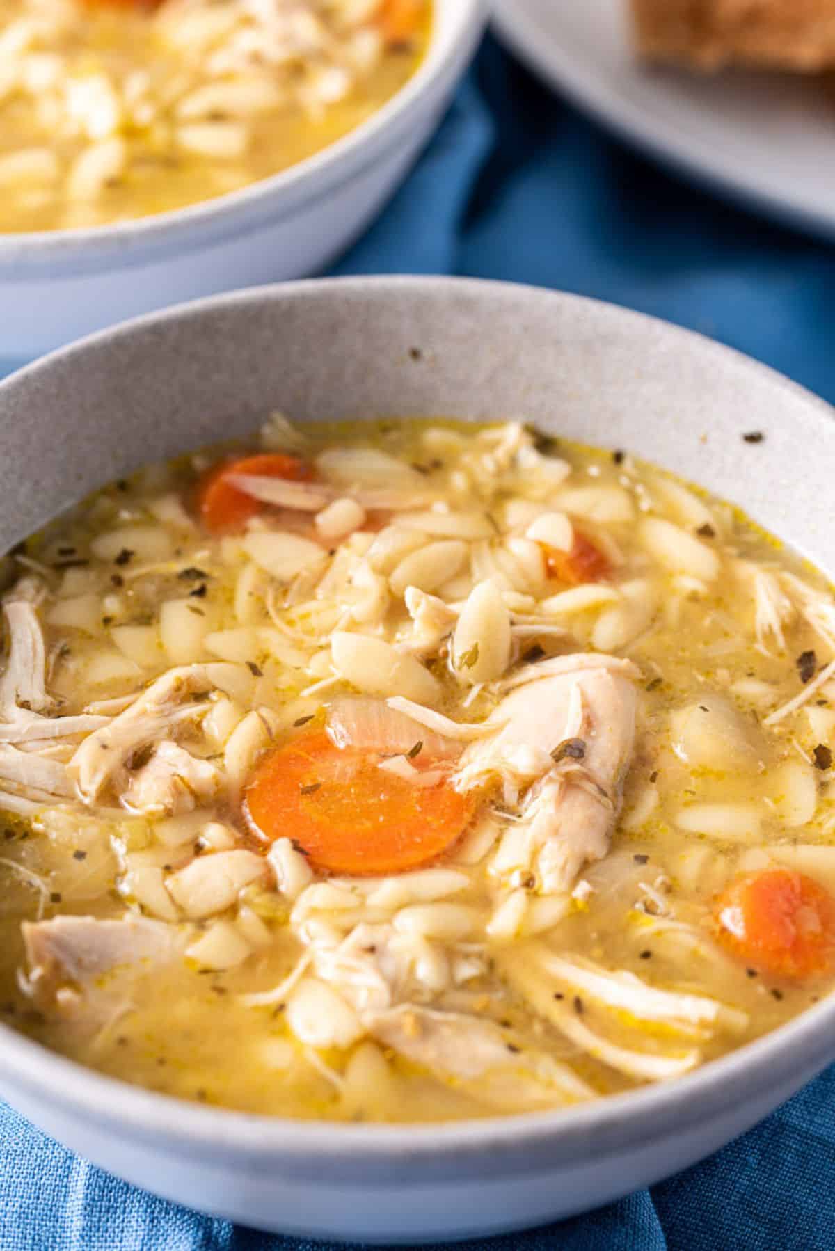 Close up view of the soup with a chicken and carrot in forefront