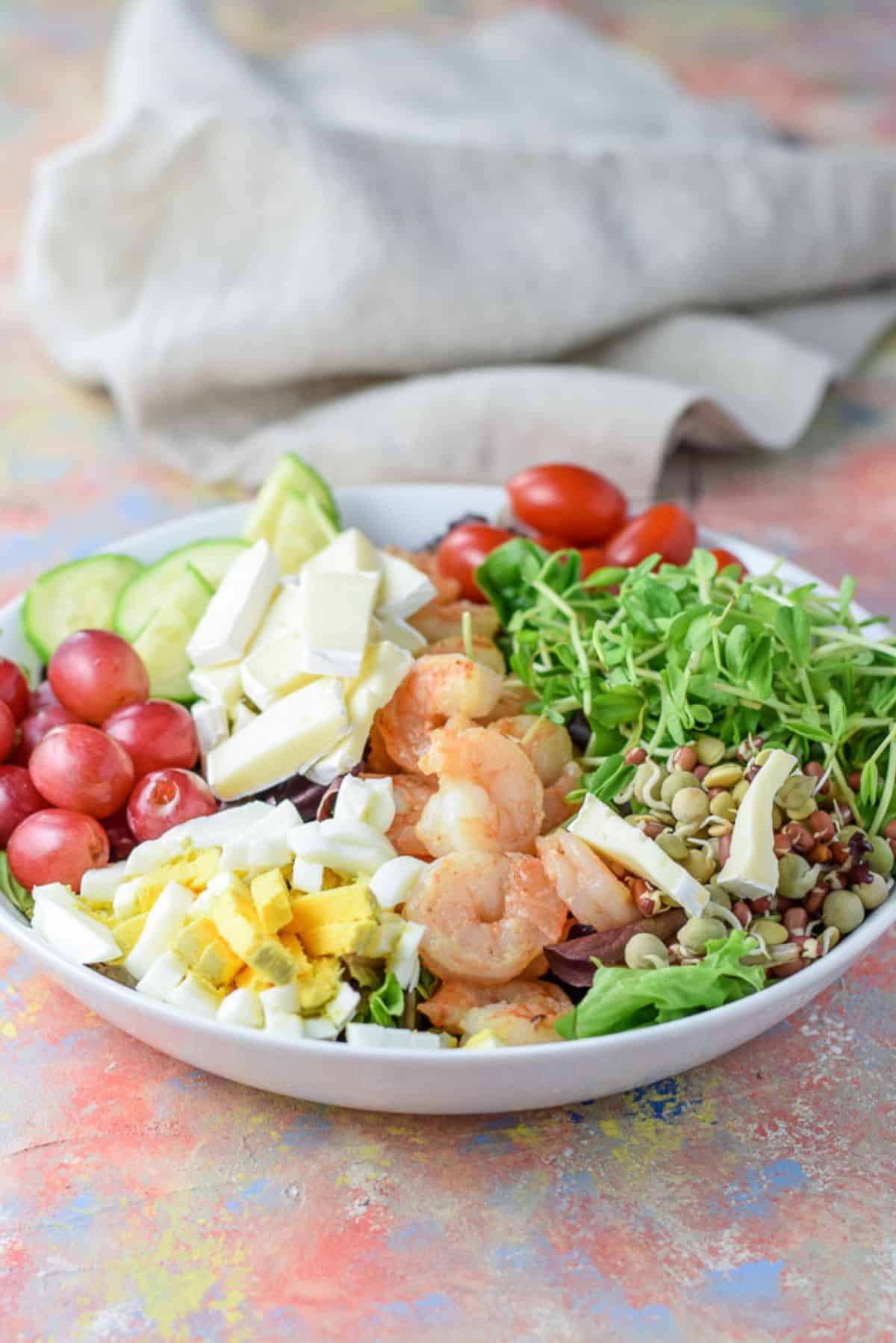 Slices of brie cheese and grapes added to the salad completing it