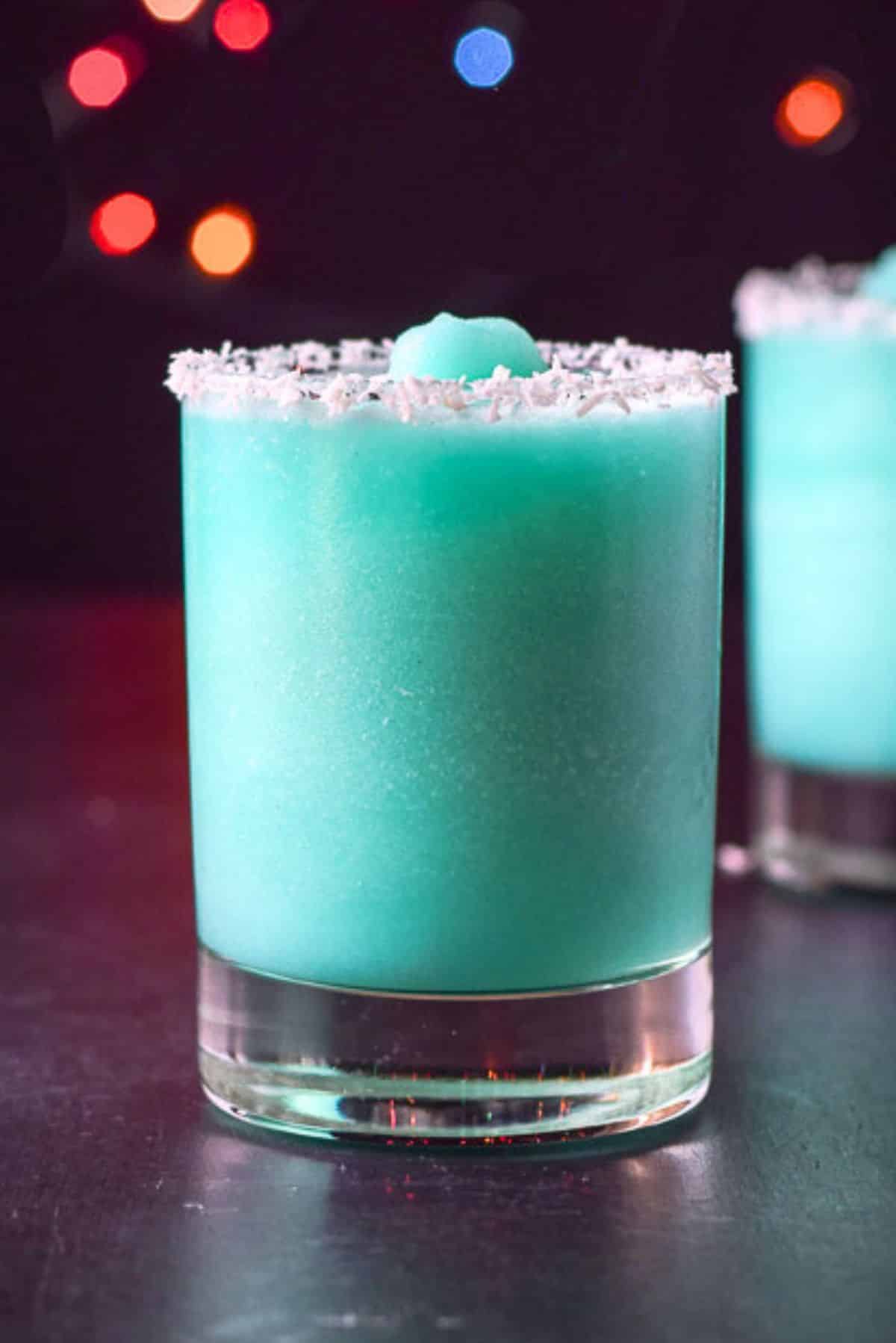 Two glasses filled with the frozen blue cocktail with coconut on the rim
