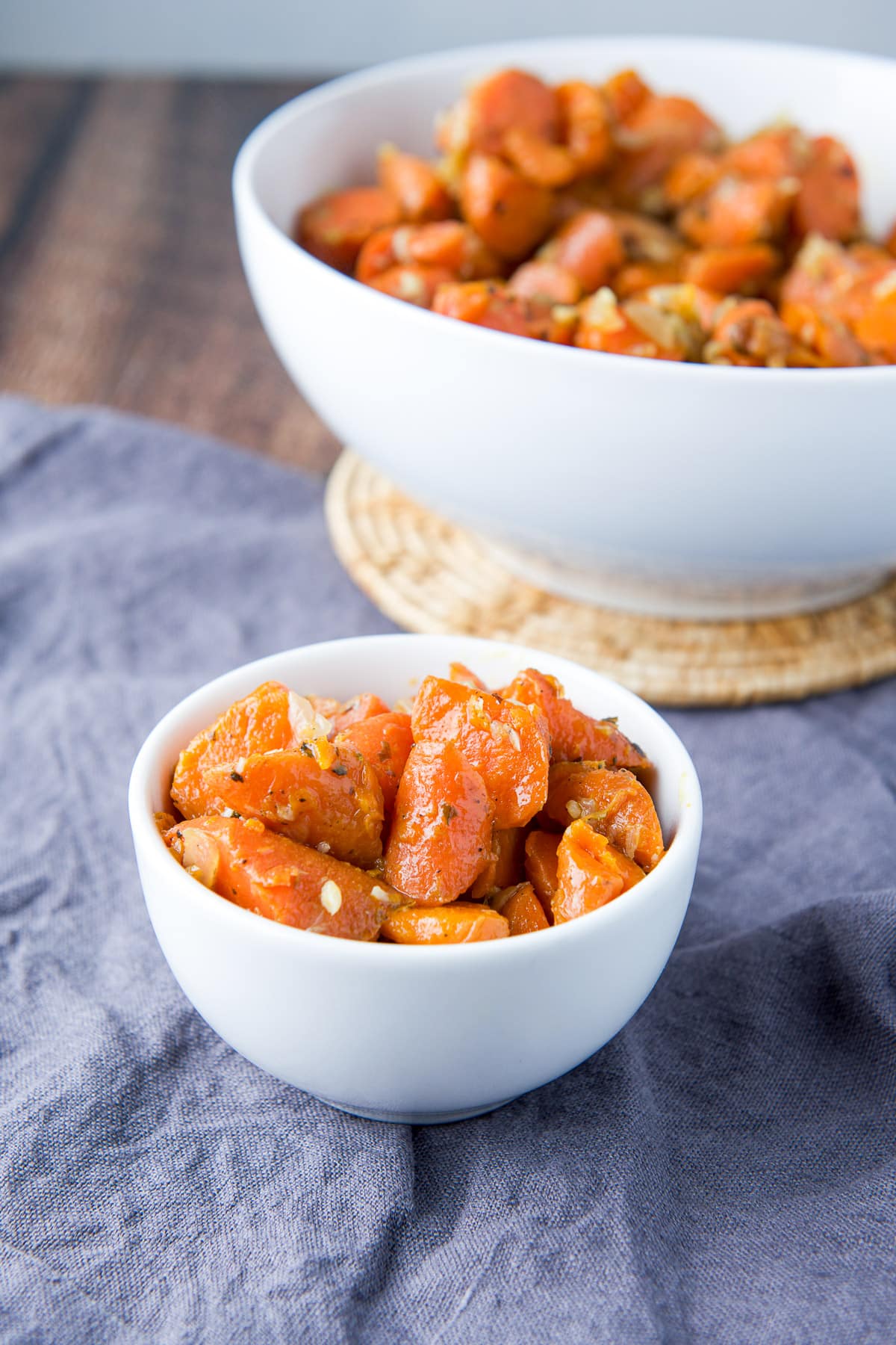 Two white bowls, one big and one small filled with carrots and onions