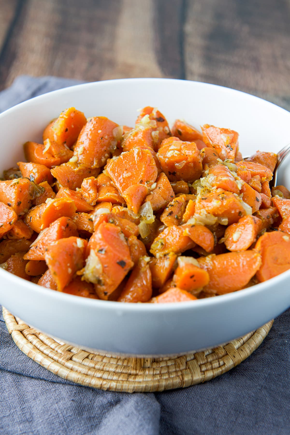 A large bowl with the cooked carrots in it on a wood table
