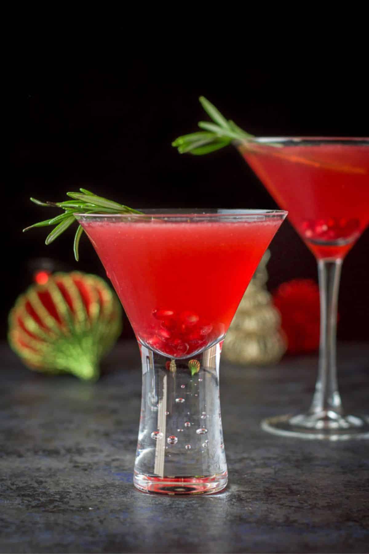 Vertical view of the bubble glass in front of the classic glass. Both filled with a red gin cocktail