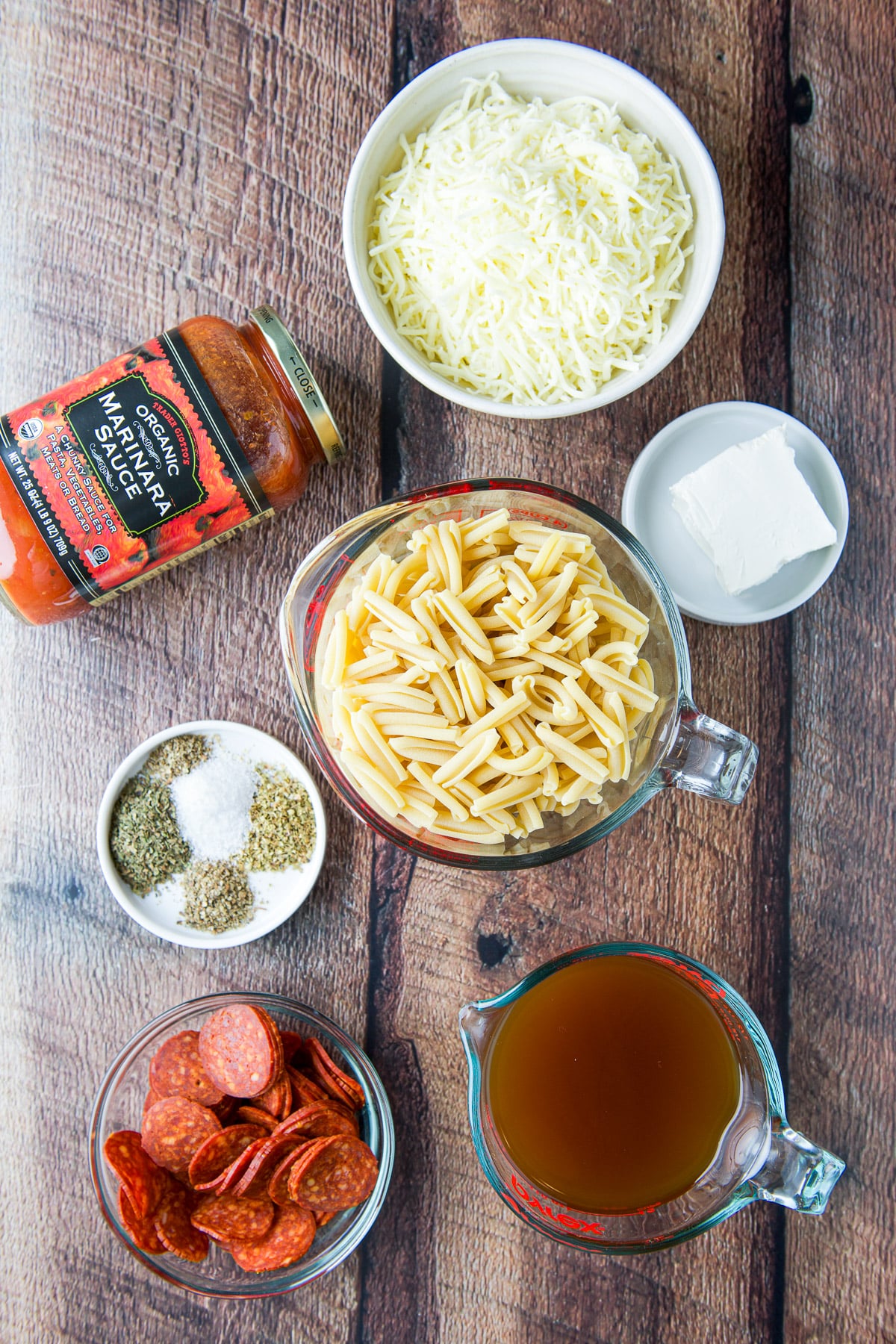 Overhead view of the ingredients - pasta, cream cheese, herbs and spices, beef broth, marinara sauce, and pepperoni