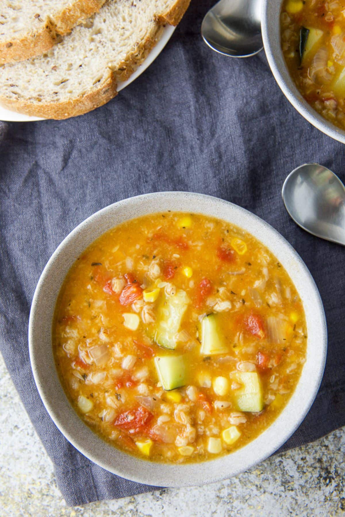 Overhead view of the soup in two bowls with two spoons and bread