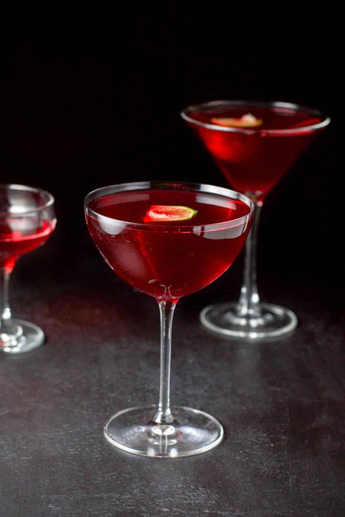 Bowl glass filled with the woo woo and a lime floating, with the classic martini glass and coupe glass behind