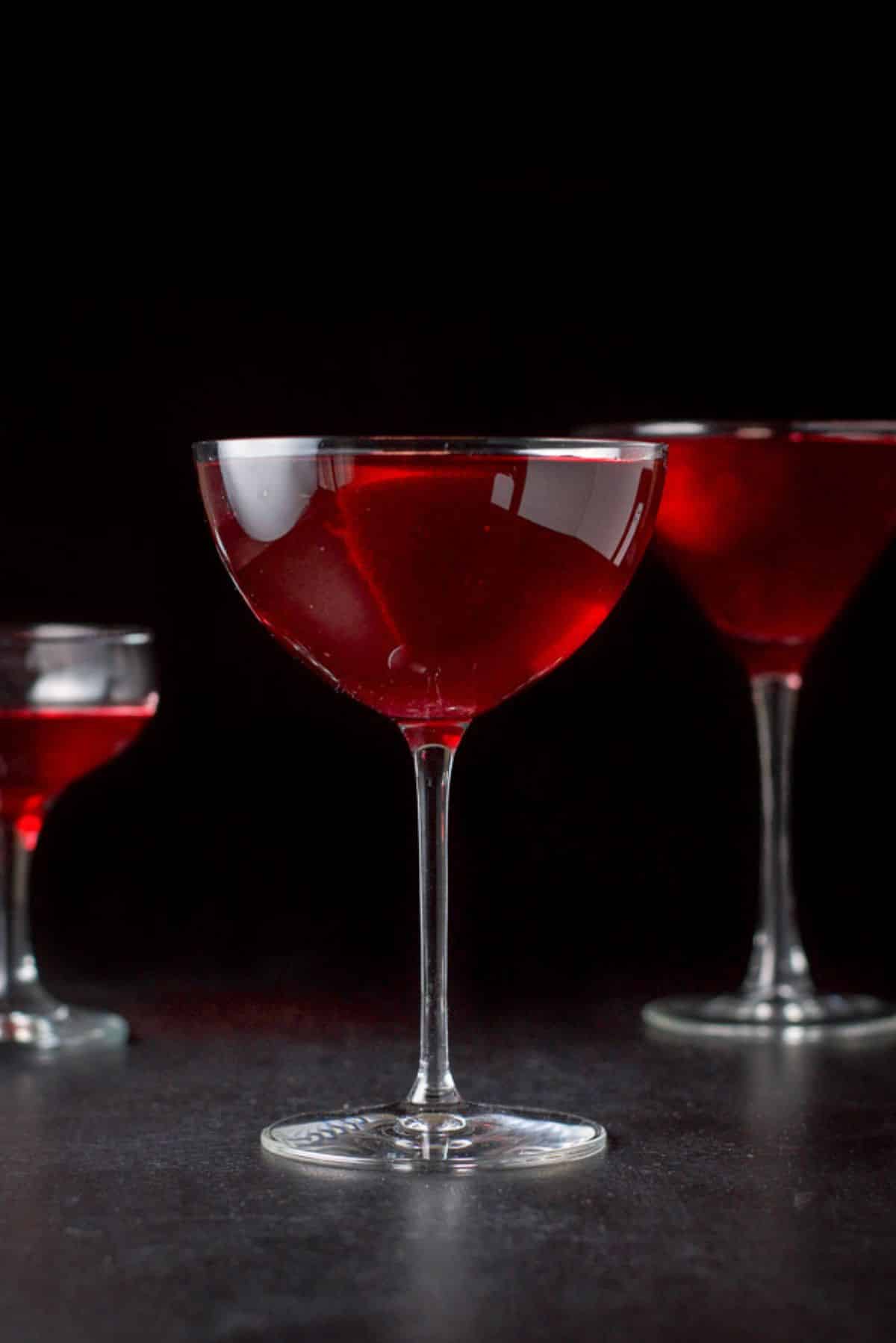 Vertical view of the red cocktail, bowl glass in front of a classic martini glass and coupe