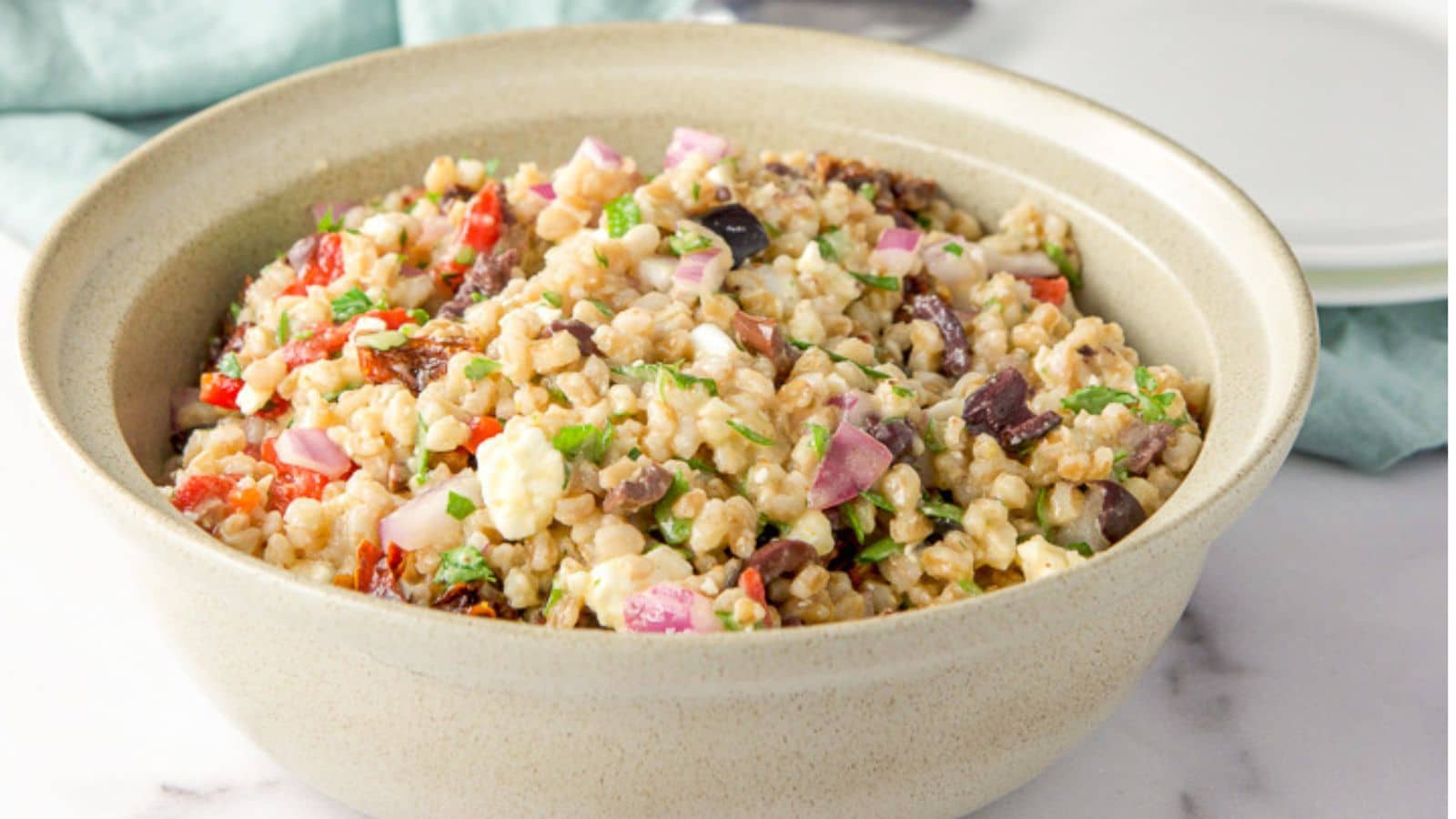 A tan bowl filled with lots of veggie and farro