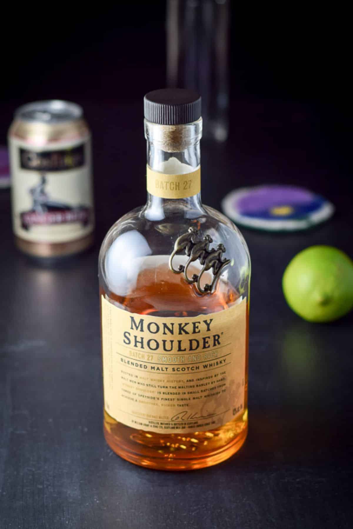 A black table with scotch, ginger beer, and lime