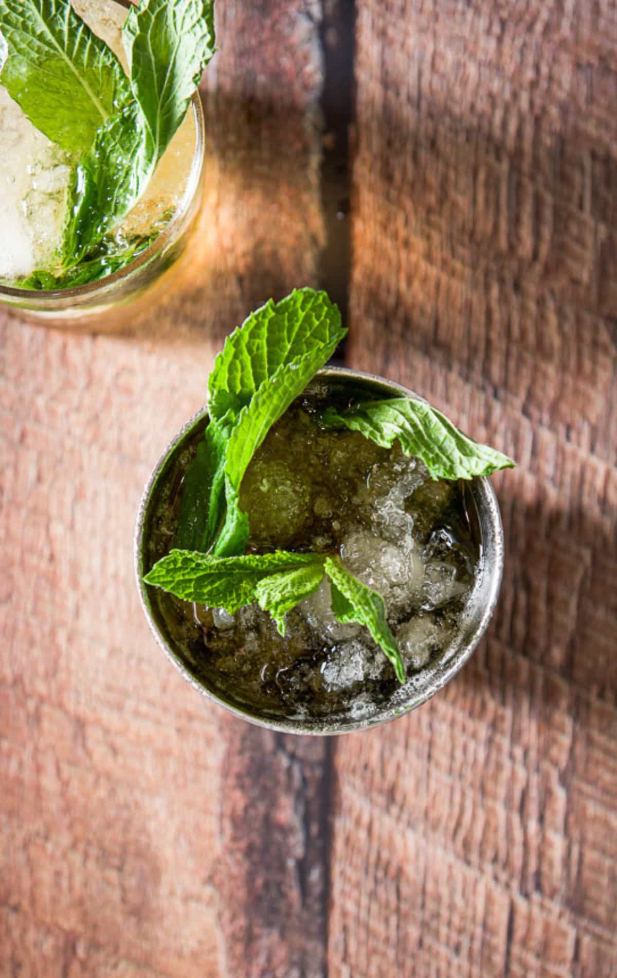Overhead view of the metal cup and glass filled with the minty bourbon drink